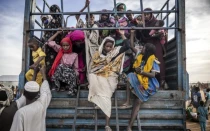 Refugiados sudaneses que huyeron de la guerra en Sudán descienden de un camión cargado de familias que llegan a un centro de tránsito para refugiados el 13 de febrero de 2024.